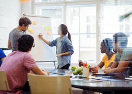A group of individuals at a white board brainstorm about the need for a customer data platform